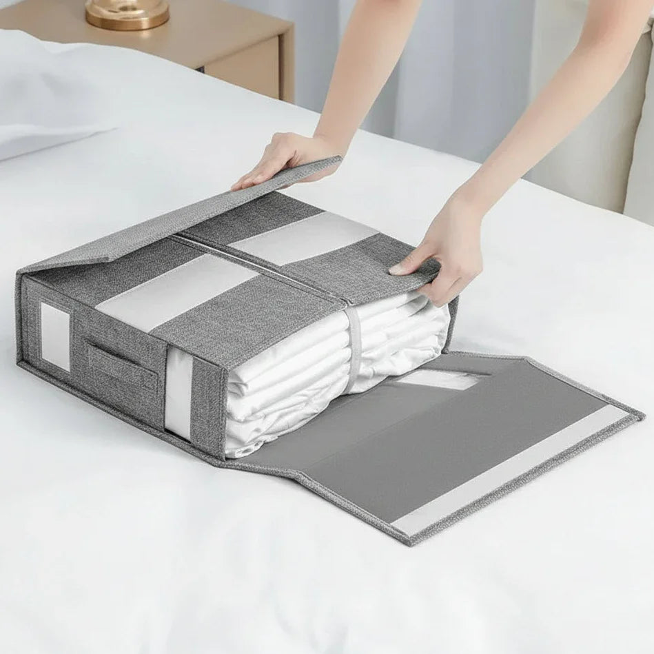 Organizador cinza de tecido para roupas e lençóis dobrados sobre cama branca